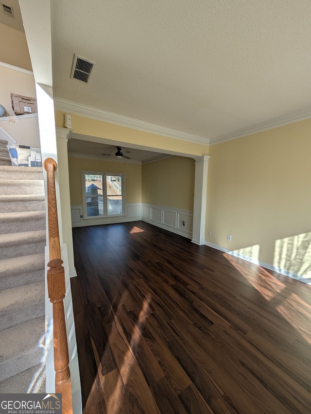 unfurnished living room featuring dark wood-style flooring, visible vents, stairway, and a textured ceiling