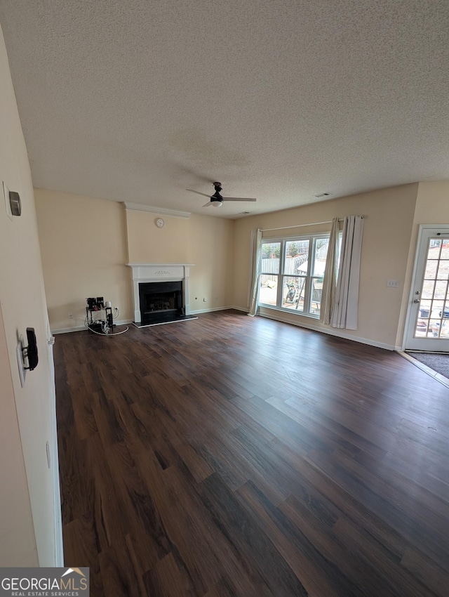 unfurnished living room with dark wood-style floors, ceiling fan, a textured ceiling, and a fireplace