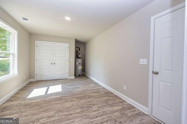 unfurnished bedroom featuring light hardwood / wood-style floors and electric water heater