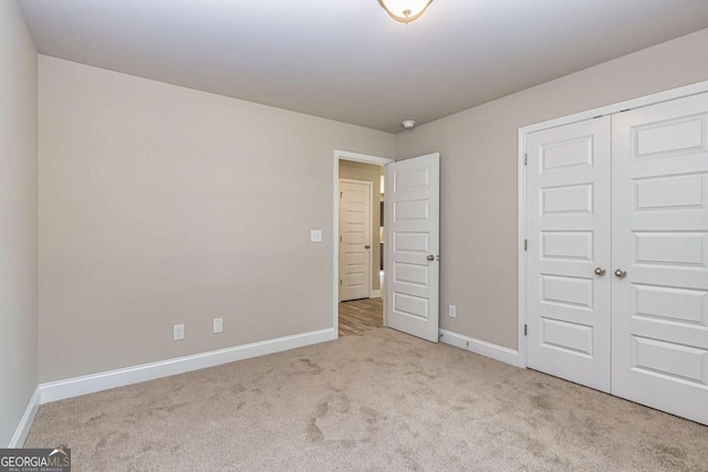 unfurnished bedroom featuring light carpet and a closet