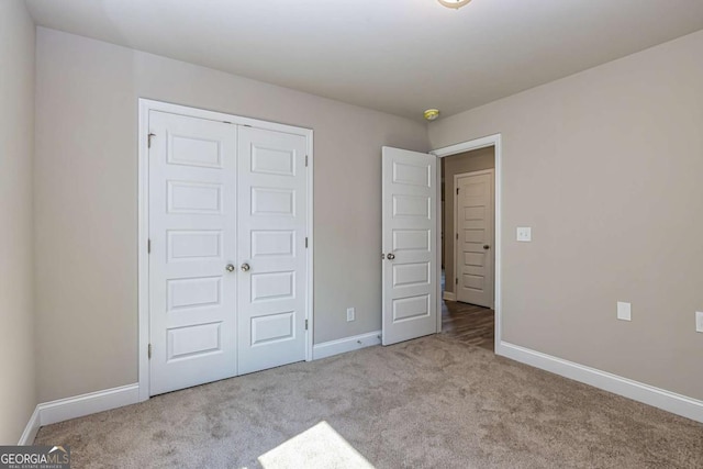 unfurnished bedroom with light colored carpet and a closet