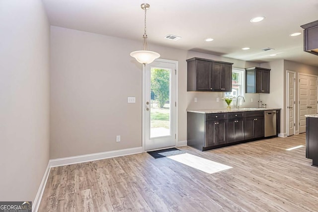 kitchen with pendant lighting, stainless steel dishwasher, dark brown cabinetry, light stone countertops, and light hardwood / wood-style flooring