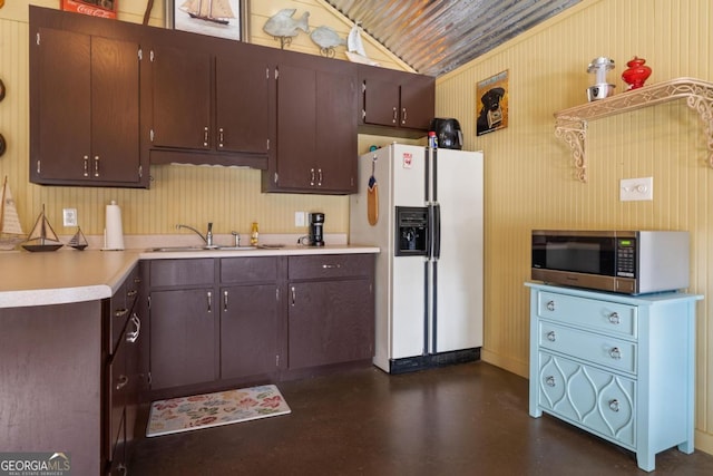 kitchen with dark brown cabinetry, lofted ceiling, sink, and white fridge with ice dispenser