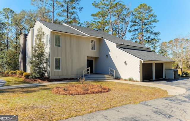 view of front of home featuring cooling unit, a garage, and a front lawn