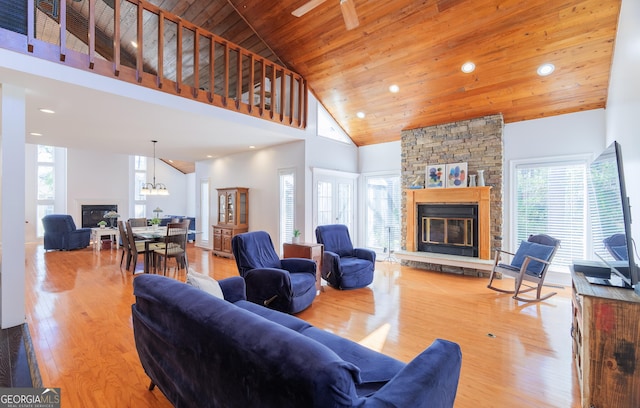 living room with wooden ceiling, plenty of natural light, a fireplace, light hardwood / wood-style floors, and a high ceiling