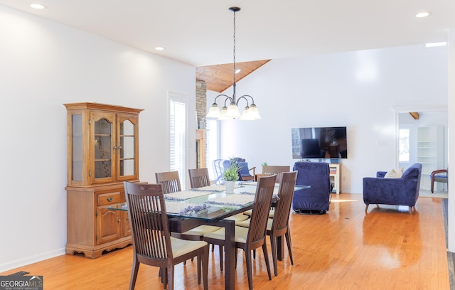 dining area featuring a towering ceiling, a chandelier, and light wood-type flooring