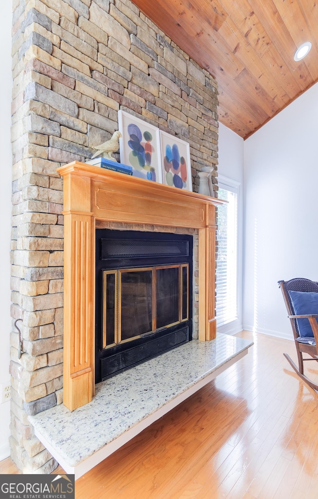 room details with hardwood / wood-style flooring, a stone fireplace, and wooden ceiling