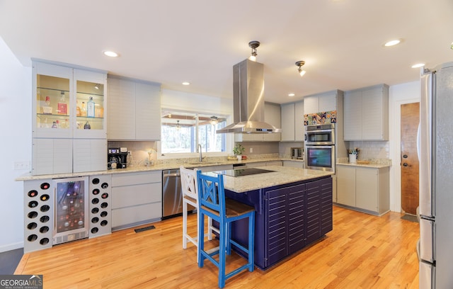 kitchen featuring backsplash, stainless steel appliances, a center island, light hardwood / wood-style floors, and island exhaust hood