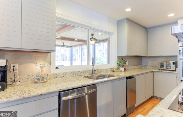 kitchen with stainless steel dishwasher, light hardwood / wood-style floors, sink, and backsplash