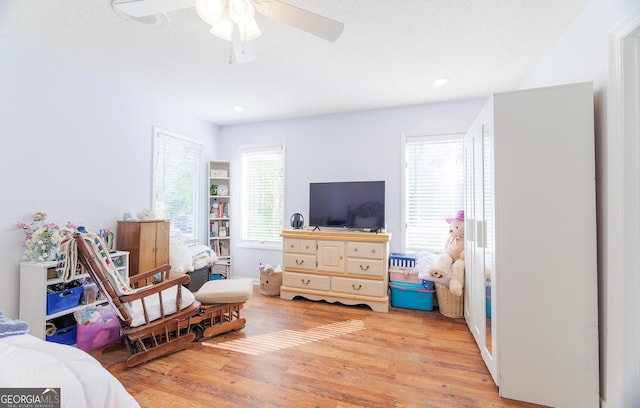 bedroom featuring light wood-type flooring, a textured ceiling, and ceiling fan