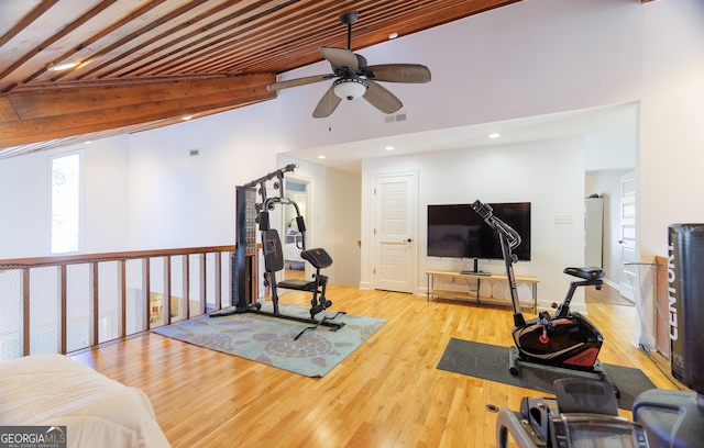 exercise room with ceiling fan, high vaulted ceiling, and light wood-type flooring