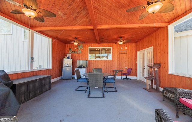 dining area featuring beamed ceiling, concrete floors, ceiling fan, and french doors