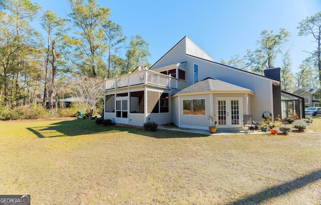 rear view of property featuring a sunroom, a lawn, and french doors