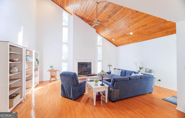 living room featuring ceiling fan, a towering ceiling, hardwood / wood-style floors, and wood ceiling