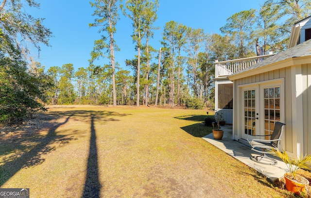 view of yard with french doors and a balcony