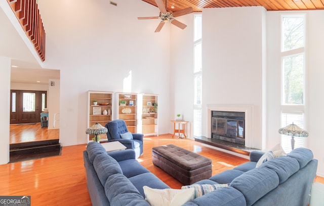 living room featuring a towering ceiling, wood ceiling, and light hardwood / wood-style flooring