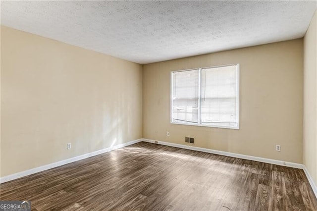 empty room with dark hardwood / wood-style flooring and a textured ceiling