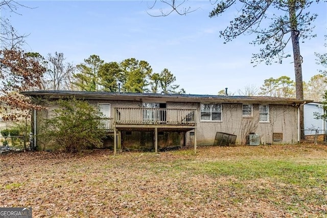 rear view of house featuring a wooden deck and a lawn