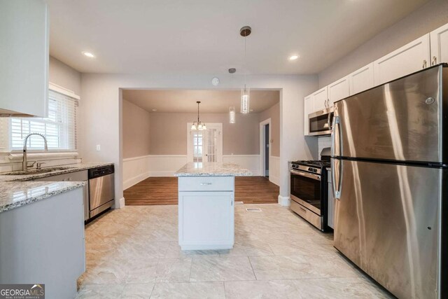 3693 Aldea Dr, Decatur, GA 30032 - kitchen featuring sink, decorative light fixtures, appliances with stainless steel finishes, a kitchen island, and white cabinets