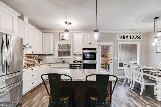 kitchen featuring white cabinetry, stainless steel appliances, a breakfast bar, and hanging light fixtures