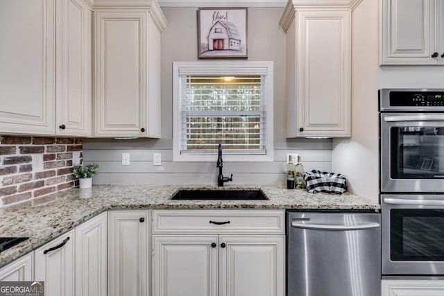 kitchen with white cabinetry, appliances with stainless steel finishes, sink, and light stone counters