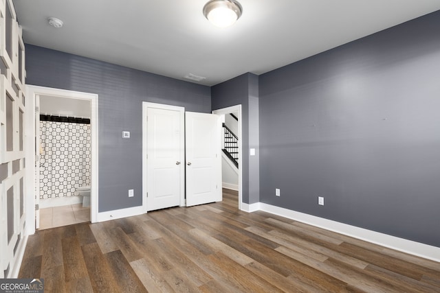 unfurnished bedroom featuring wood-type flooring and ensuite bathroom