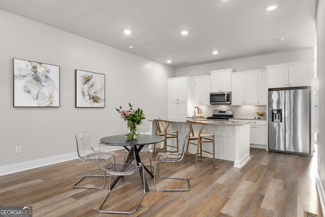 dining space with sink and wood-type flooring