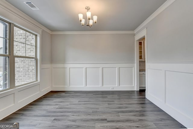 unfurnished dining area with an inviting chandelier, hardwood / wood-style floors, and ornamental molding