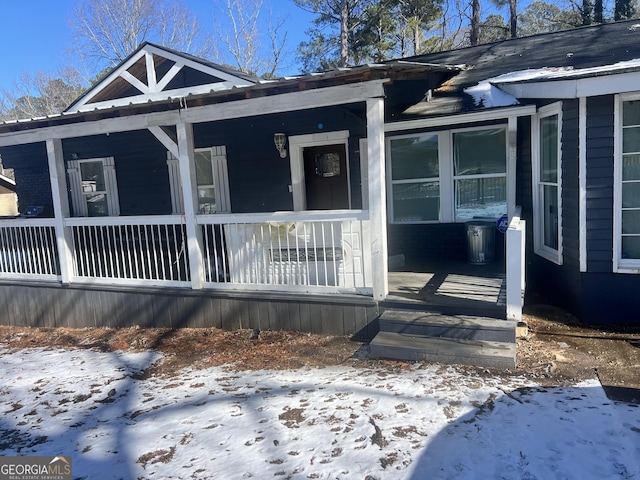 snow covered property entrance featuring covered porch