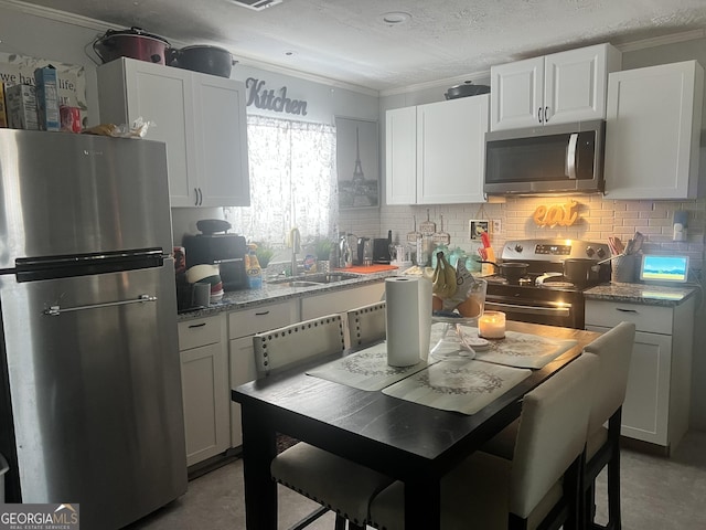 kitchen featuring light stone counters, appliances with stainless steel finishes, sink, and white cabinets