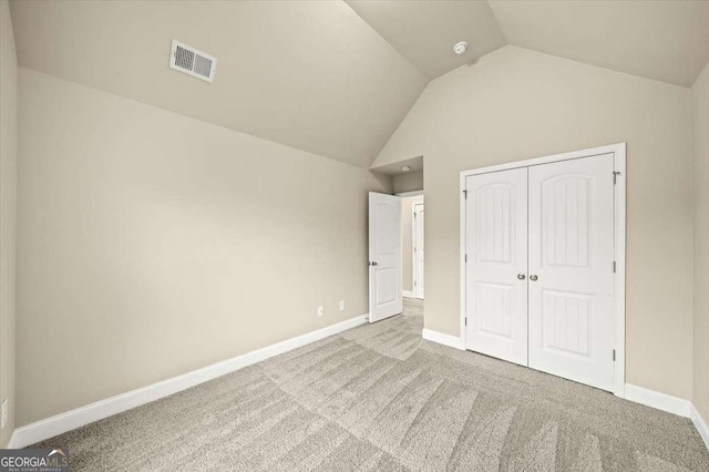 unfurnished bedroom featuring vaulted ceiling, light colored carpet, and a closet