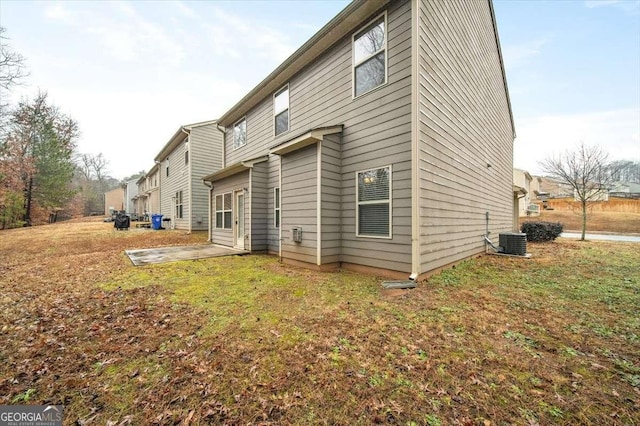 rear view of property with a patio, central AC, and a lawn