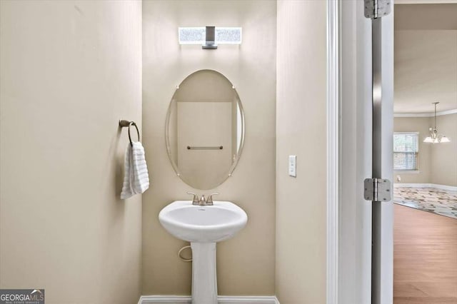 bathroom featuring an inviting chandelier, hardwood / wood-style flooring, and ornamental molding