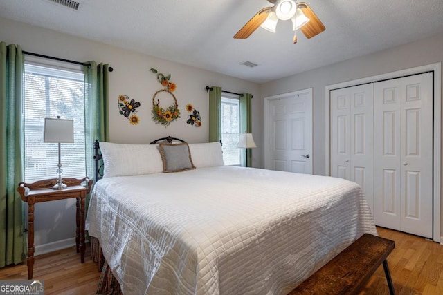 bedroom featuring two closets, light hardwood / wood-style flooring, and ceiling fan