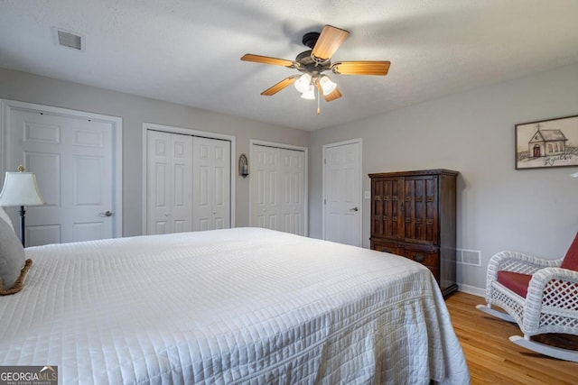 bedroom featuring multiple closets, ceiling fan, and light wood-type flooring