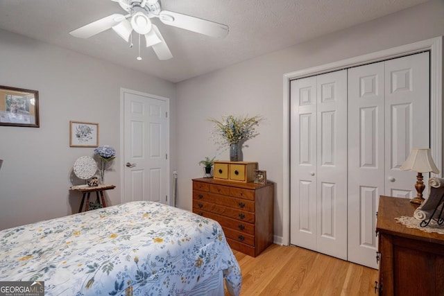 bedroom featuring ceiling fan, a closet, light hardwood / wood-style flooring, and a textured ceiling