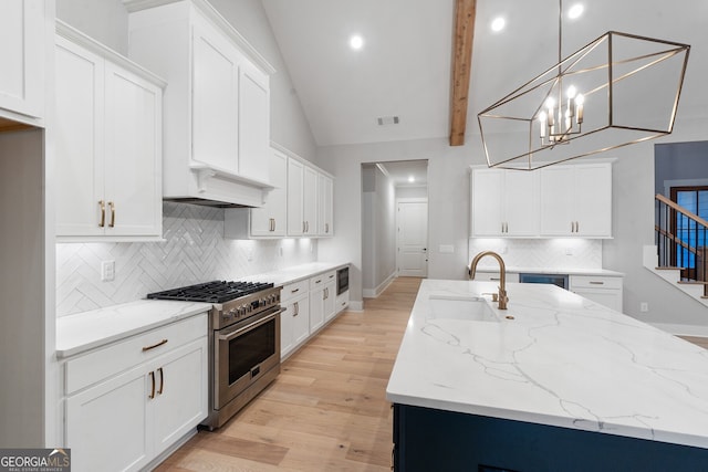 kitchen featuring pendant lighting, stainless steel range, sink, and white cabinets