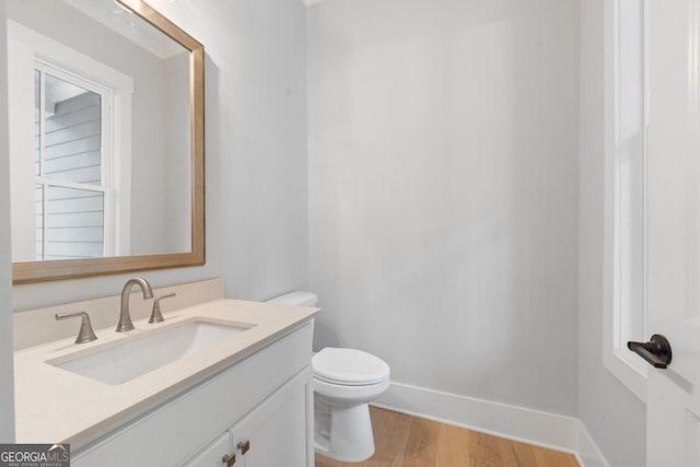 bathroom with wood-type flooring, vanity, and toilet