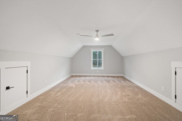 additional living space with vaulted ceiling, light colored carpet, and ceiling fan