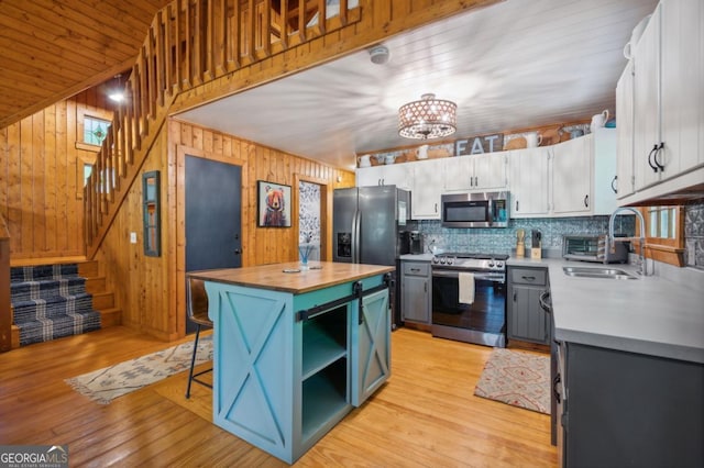 kitchen with sink, white cabinetry, a center island, light wood-type flooring, and appliances with stainless steel finishes