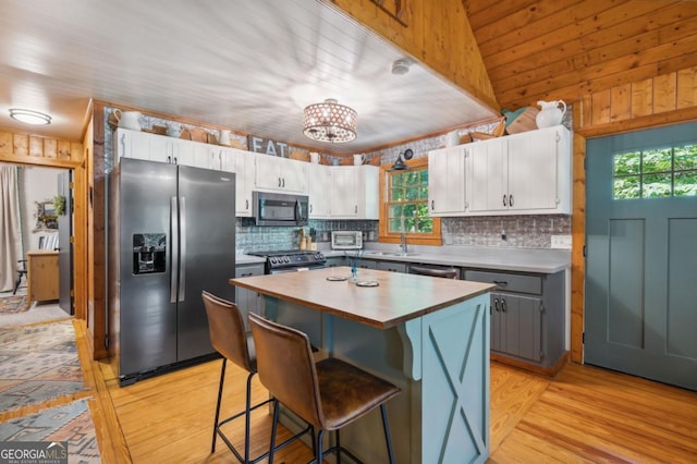 kitchen featuring a breakfast bar area, gray cabinetry, white cabinetry, a center island, and appliances with stainless steel finishes