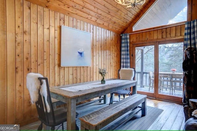 dining space with wooden walls, vaulted ceiling, hardwood / wood-style floors, and wooden ceiling