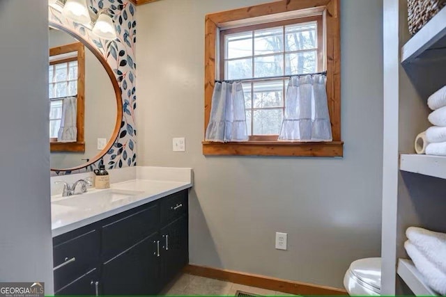 bathroom featuring plenty of natural light, toilet, and vanity