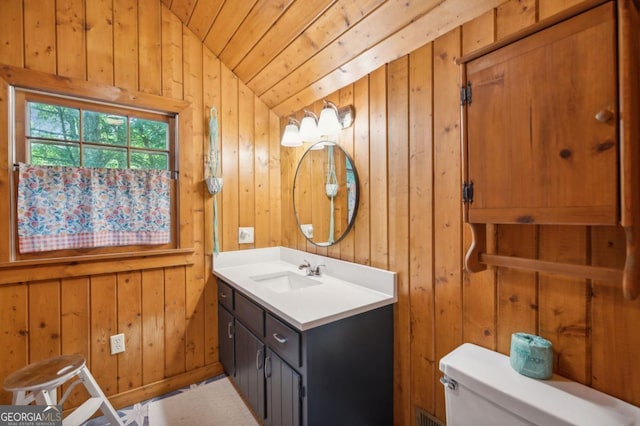 bathroom featuring vaulted ceiling, toilet, and wood walls