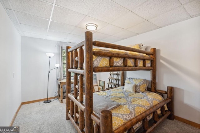 bedroom featuring a drop ceiling and carpet