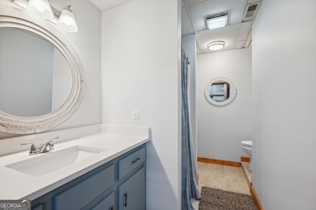 bathroom featuring tile patterned floors, vanity, toilet, and a drop ceiling