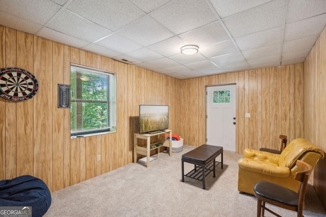 carpeted living room featuring a paneled ceiling and wooden walls