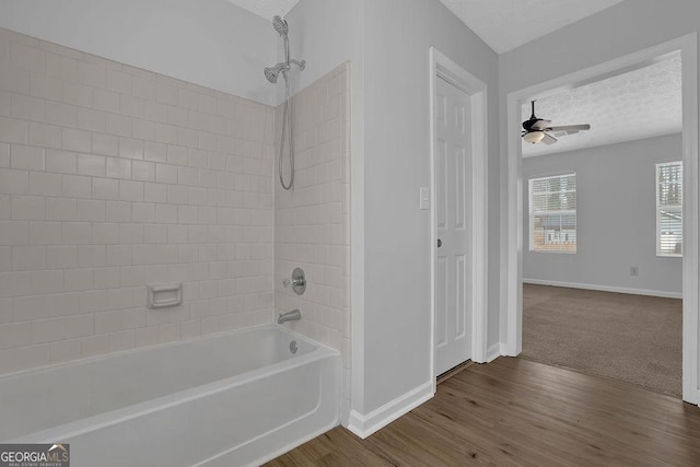 bathroom featuring ceiling fan, tiled shower / bath, wood-type flooring, and a textured ceiling