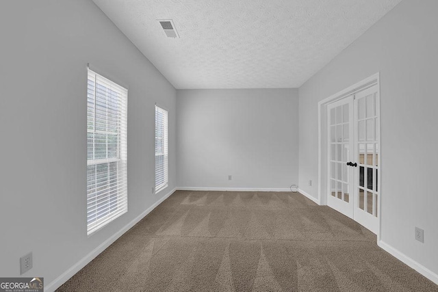 empty room with french doors, carpet floors, and a textured ceiling