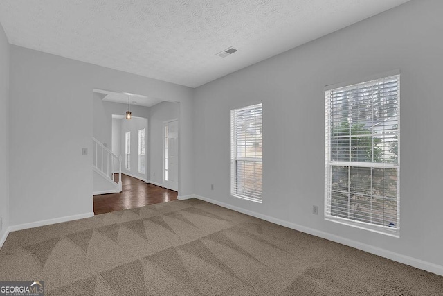 unfurnished room with carpet flooring and a textured ceiling